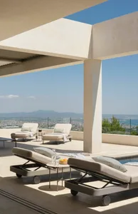 A modern, minimalist patio area featuring concrete surfaces and furniture.