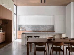 A minimalist residential kitchen featuring marble countertops, concrete backsplash, and wooden furniture.