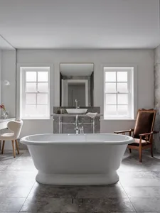 Modern bathroom interior with marble bathtub, sink, and chairs.