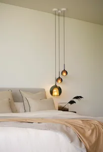 A modern bedroom featuring minimalist design with hanging pendant lights and neutral textiles, creating a cozy atmosphere.