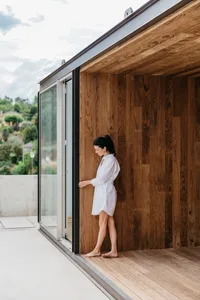A modern exterior space featuring wooden flooring and a wooden wall.