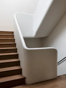 Modern interior staircase with concrete steps and wooden railings.