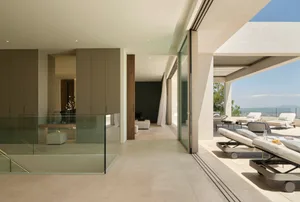 Contemporary living space with glass walls and modern furniture, featuring a comfortable lounge area and a stunning outdoor t