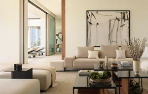 Modern living room with beige furniture, white walls, and black and white artwork.