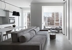 Modern living room with a concrete floor, a gray sectional sofa, and a minimalist design.