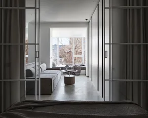 A modern living room featuring a concrete sectional sofa and a circular ottoman with a book on top.