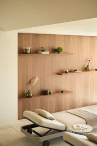 A modern living room with wooden accents, a chaise lounge, and floating shelves.