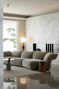 A contemporary living room featuring a modern sofa, marble fireplace wall, and minimalist decor.