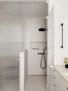 Modern minimalist bathroom with glass enclosure shower and porcelain fixtures.