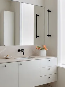 Minimalist bathroom featuring a granite countertop, white cabinets, and a sleek black sink faucet.