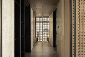 A minimalist corridor with wooden walls and a wooden ceiling, featuring a grid-patterned glass door.