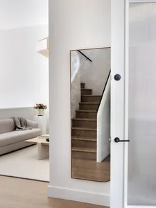A minimalist home interior with hardwood stairs and a light-colored sofa.
