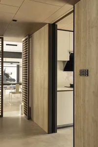 A modern minimalist kitchen with an open-concept layout, showcasing sleek, light-colored wooden cabinetry and a smooth, conti