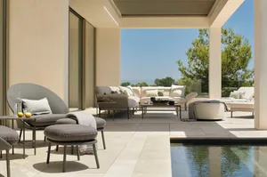 Modern patio featuring cement tiles with outdoor seating including sofas, ottomans, and tables, alongside a swimming pool wit