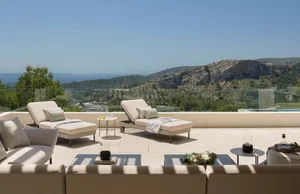 Modern patio featuring concrete and glass furniture with a scenic mountain view.