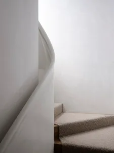 Modern staircase with neutral textiles in a white room