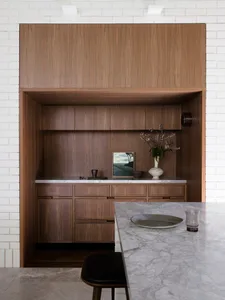 Minimalist kitchen area with wooden cabinetry and marble countertops.