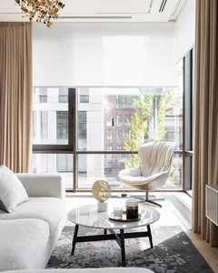 A modern living room with a white sofa, textured flooring, and large windows