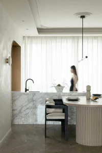 A modern minimalist kitchen featuring marble countertops and a white curtain.