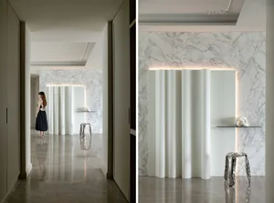 A modern minimalist living room with marble walls and floors, featuring sleek, clean lines and a serene ambiance.