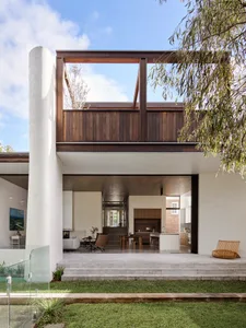 Modern residential building featuring large windows, wooden accents, and concrete steps.