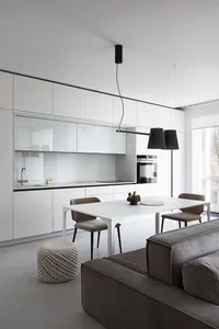 Modern kitchen and dining area featuring minimalist white cabinets, black accents, and hardwood floors.