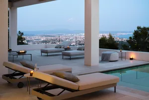A modern pool deck with concrete seating areas overlooking a cityscape at dusk.
