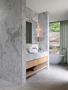 Modern bathroom featuring marble walls and oak vanity.