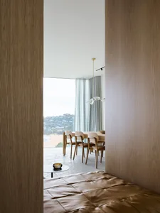 Modern dining room featuring wooden furniture and large windows overlooking a scenic view.