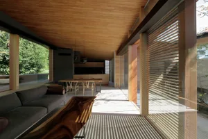 A modern coastal living room with wooden accents, featuring a comfortable sofa, a wooden bench, and a dining area with a whit
