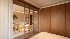 A minimalist bedroom with wooden paneling and a large bed.