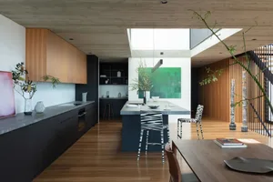 An image of a modern minimalist residential kitchen featuring black stainless steel appliances and wood accents.