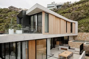 Modern residential exterior featuring concrete, wood, and glass materials.