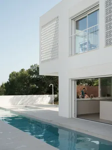 A modern residential space featuring a white stone floor and large windows.