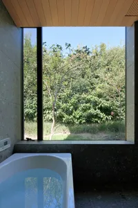 A minimalist bathroom featuring a glass window overlooking greenery.