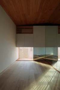 Minimalist design interior with wooden flooring and light filtering through a lattice window.