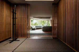 A minimalist residential interior featuring wood paneling, textiles, and concrete flooring.