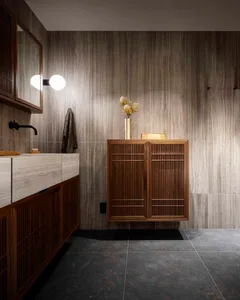 A modern bathroom with wooden cabinets and marble tiles.