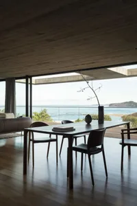 Modern dining room with a glass wall overlooking the ocean.