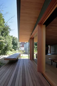 Modern exterior of a house with wooden flooring and a wooden bench on a deck.