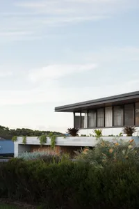 A modern house with a concrete exterior, featuring large windows and a rooftop garden.