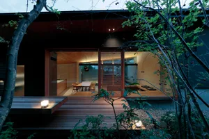 A modern house exterior with wooden planks and illuminated windows.