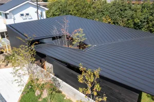 A modern house with a metal roof on a hillside.