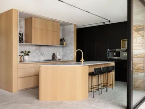 A modern kitchen with wooden cabinets and marble countertops.