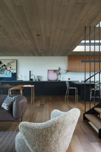 Modern living room with a wood floor, minimalist furniture, and a mix of textures including a furry white chair and a concret