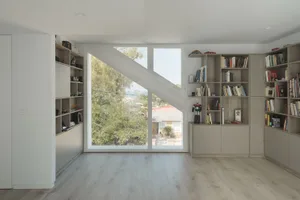 A modern living room featuring wooden shelves, floor-to-ceiling windows, and a minimalist design.