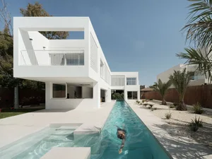 A modern minimalist house with a concrete and glass facade.