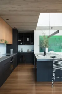 Contemporary residential kitchen featuring minimalist design, concrete countertops, wooden cabinets, and stone accents.