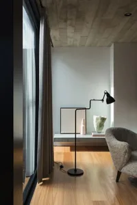A modern minimalist living room featuring concrete elements and a floor lamp.
