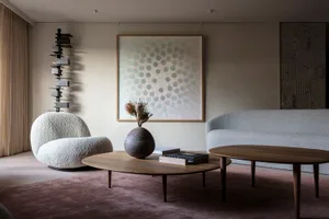 A modern minimalist living room featuring a marble coffee table, wooden sofa, and plush fabric chairs.